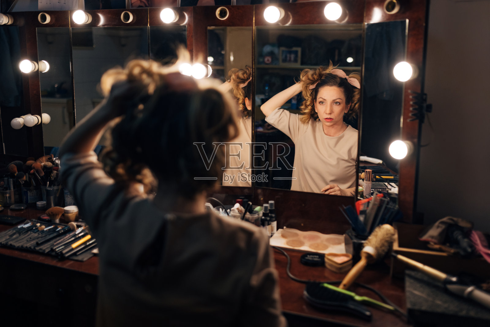 一位戏剧演员正在为演出做准备，她正在整理头发和化妆照片摄影图片