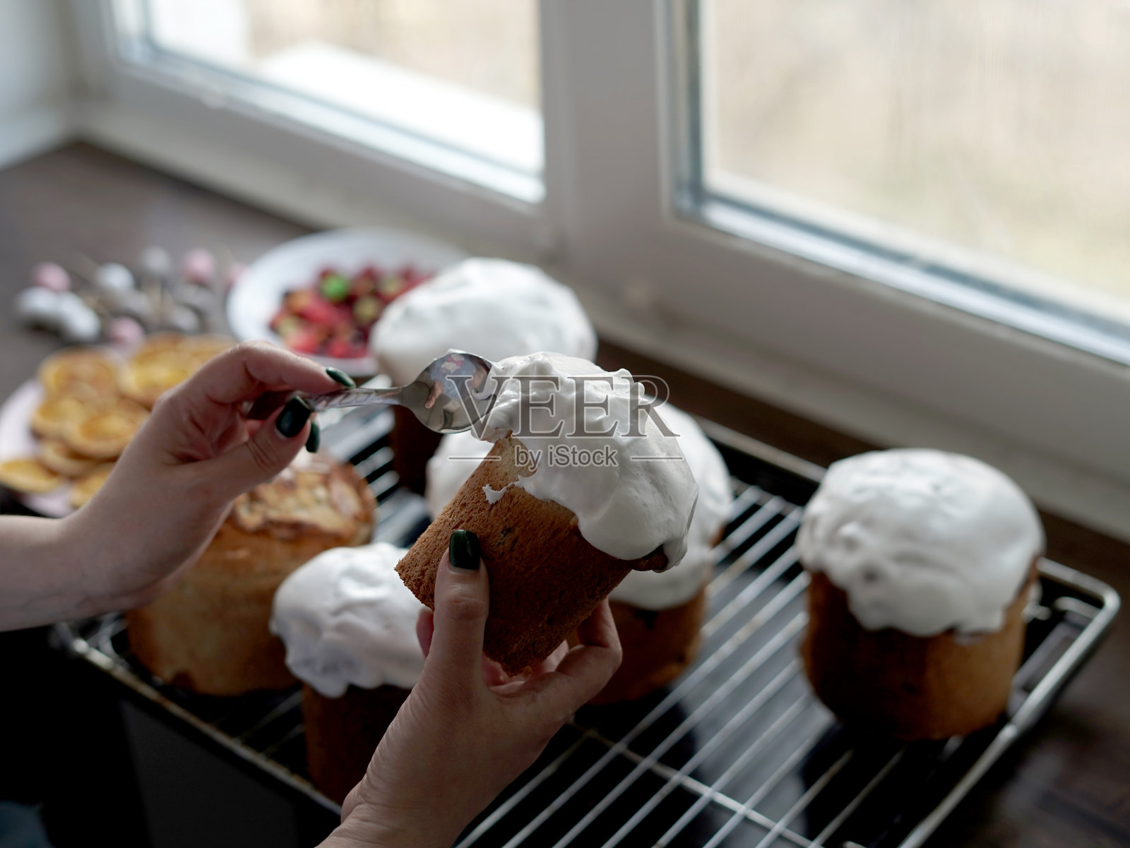 白人妇女的手在刚煮好的复活节蛋糕上涂白釉。自制传统复活节蛋糕照片摄影图片
