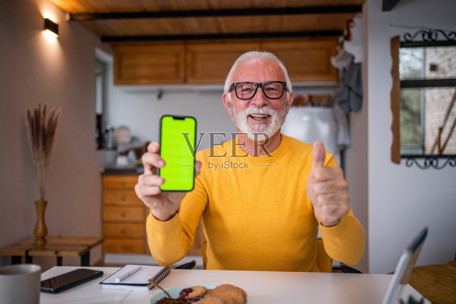 快乐微笑的老年男子展示手机与绿色屏幕照片摄影图片