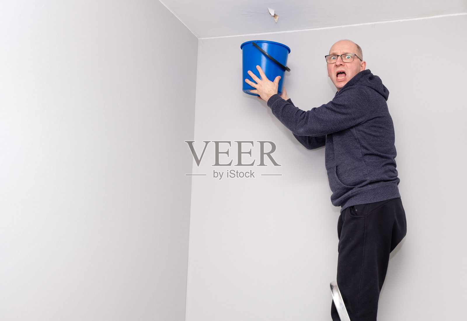 白人男子手里拿着一个蓝色的桶。男人很生气。照片摄影图片