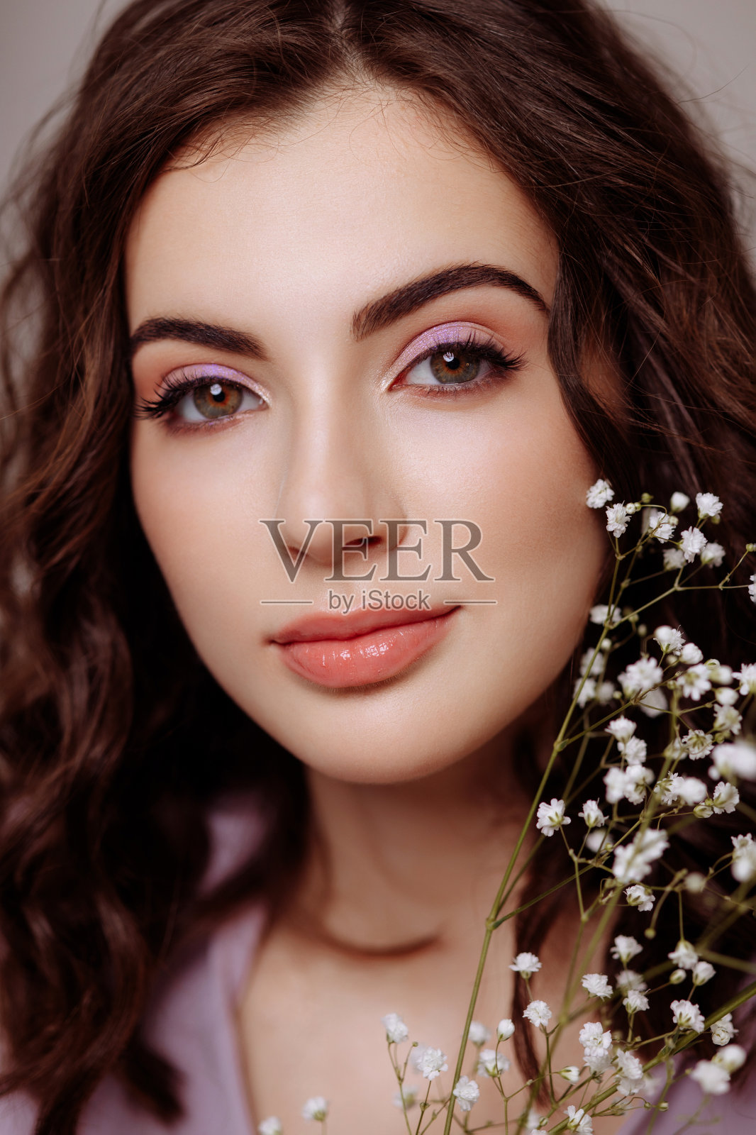 一个黑发女孩手里拿着一束吉卜草花。照片摄影图片