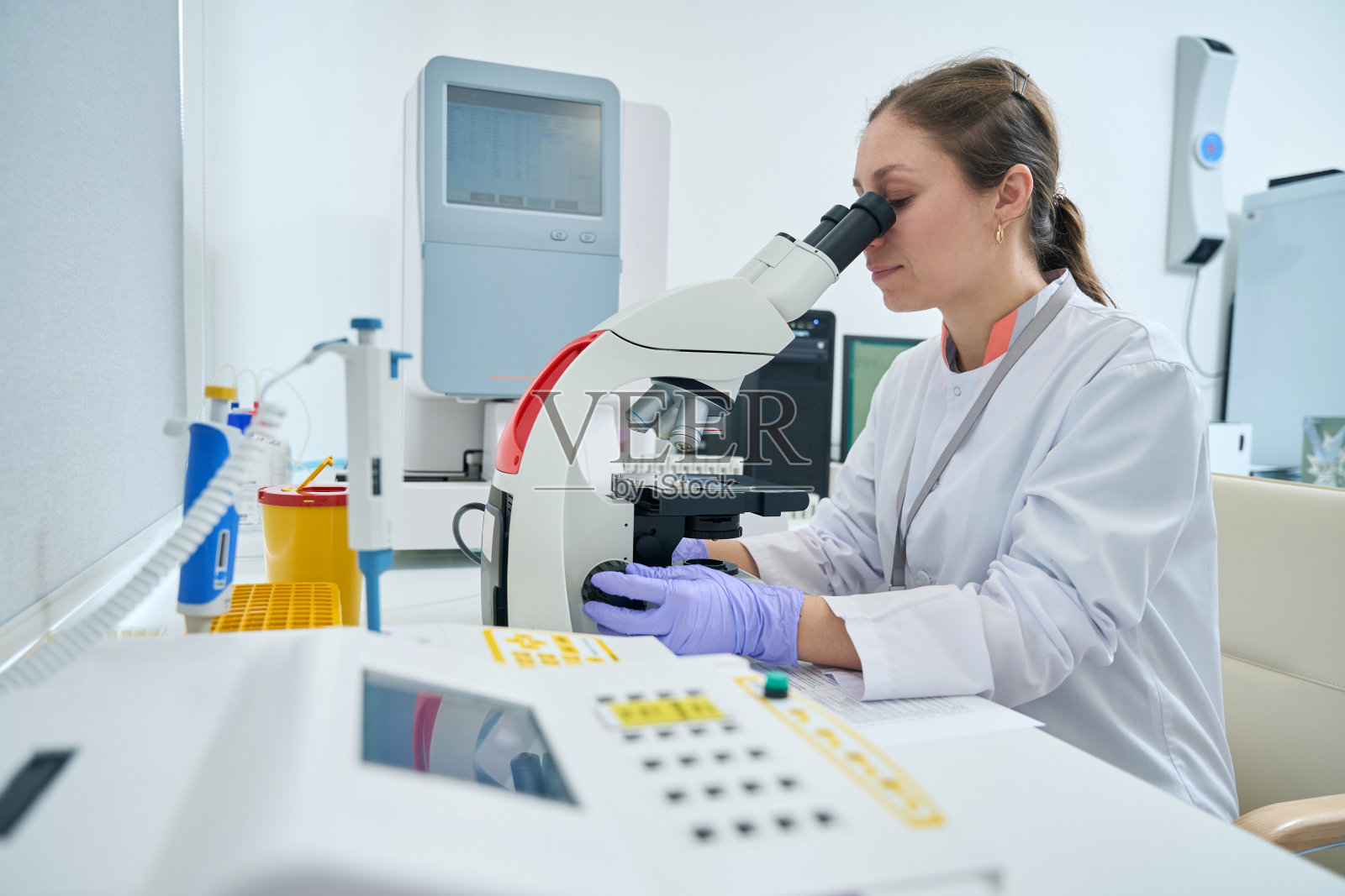 实验室工作人员看着显微镜的目镜照片摄影图片