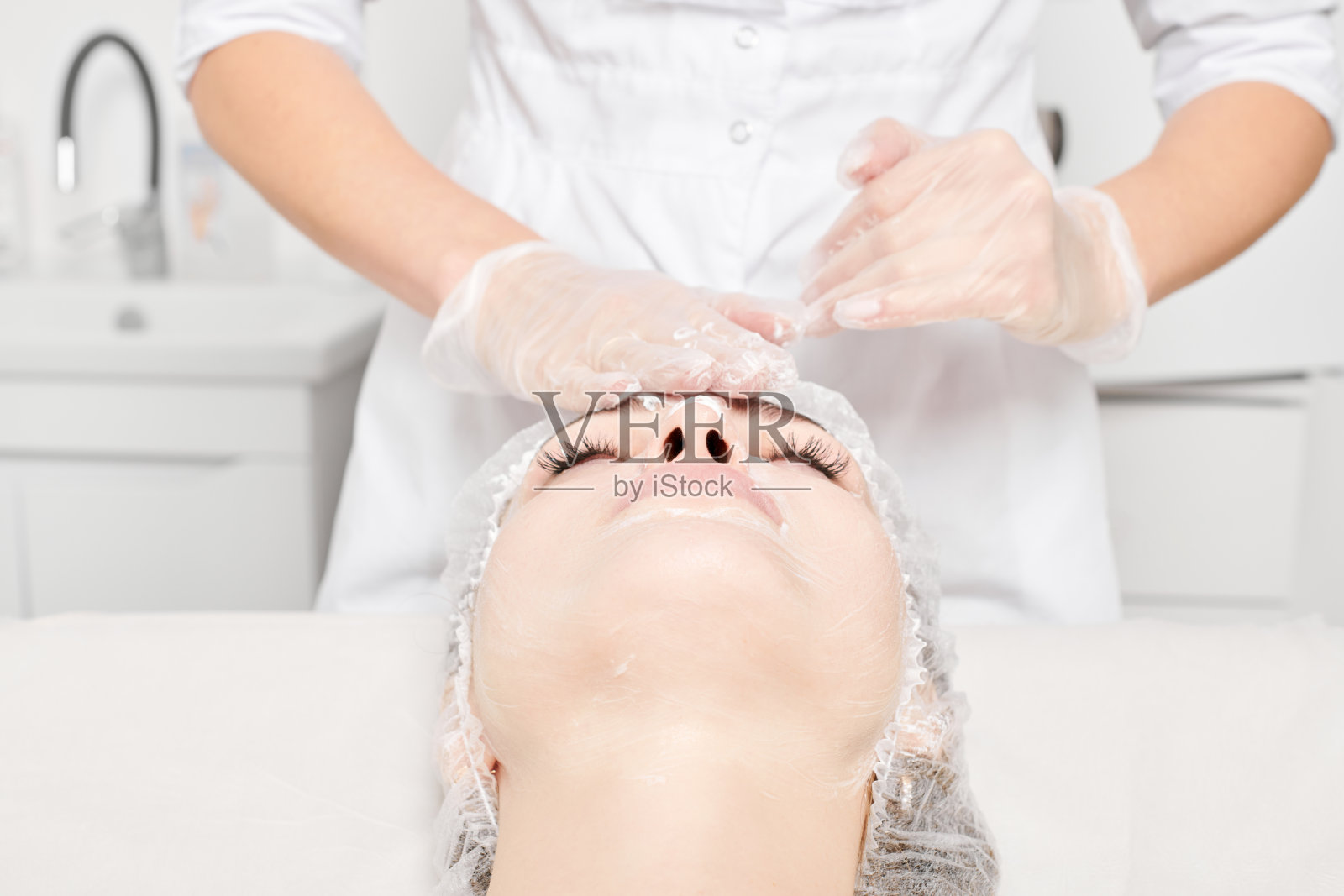 美容师在美容院按摩奶油面膜到女性面部皮肤以恢复活力照片摄影图片