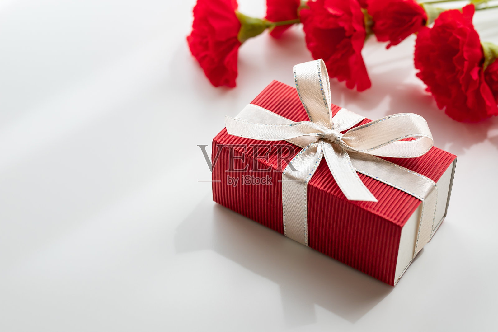 母亲节礼物盒和白色背景的红色康乃馨。照片摄影图片
