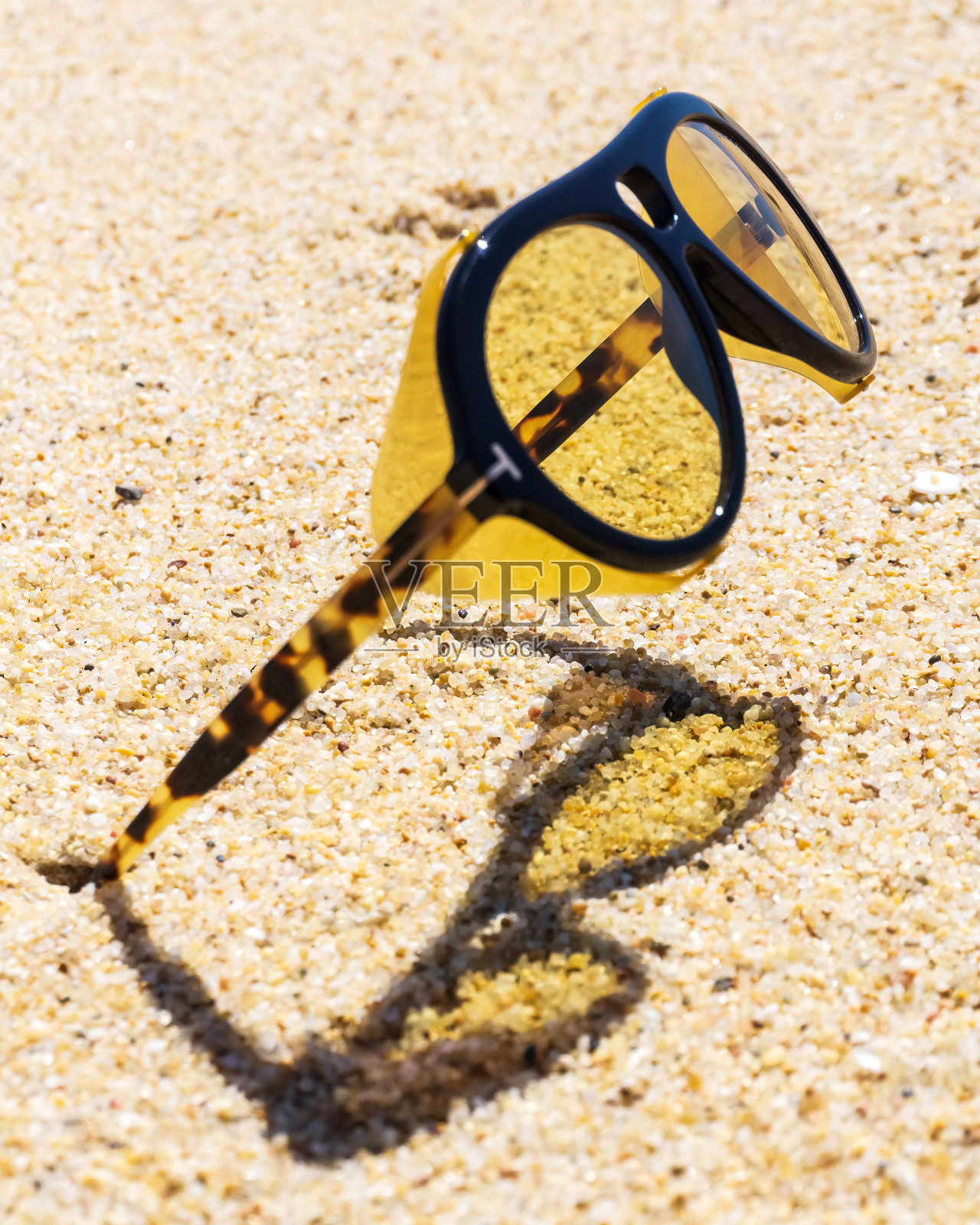 不寻常的黄色太阳镜卡在沙滩上的沙子里照片摄影图片