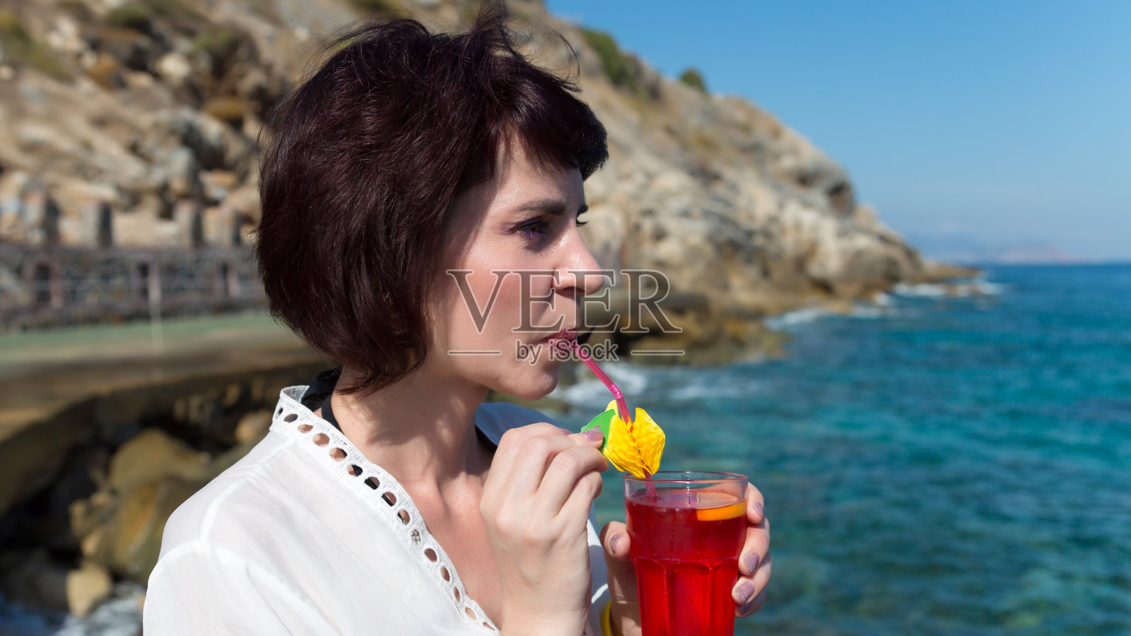 夏日炎炎，一个女孩在海边用吸管喝果汁照片摄影图片
