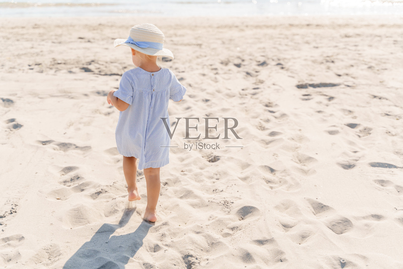 海边海滩上戴草帽的小女孩，背影照片摄影图片