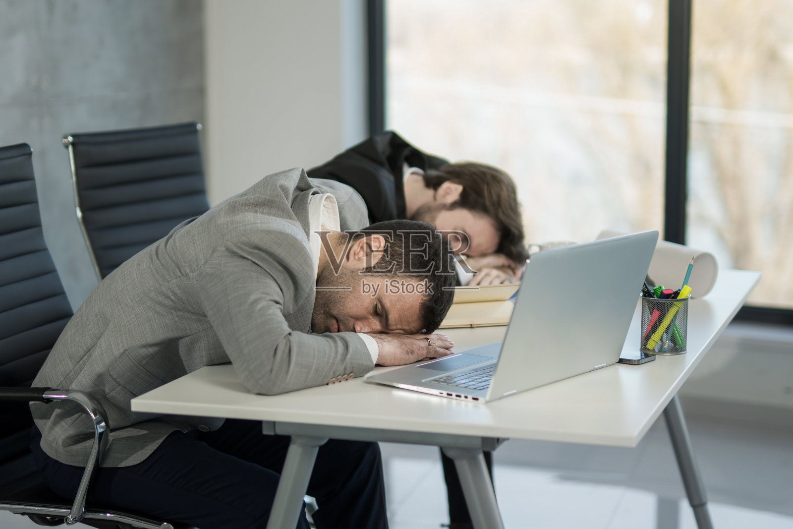 两个精疲力竭的商人在办公室睡觉。照片摄影图片