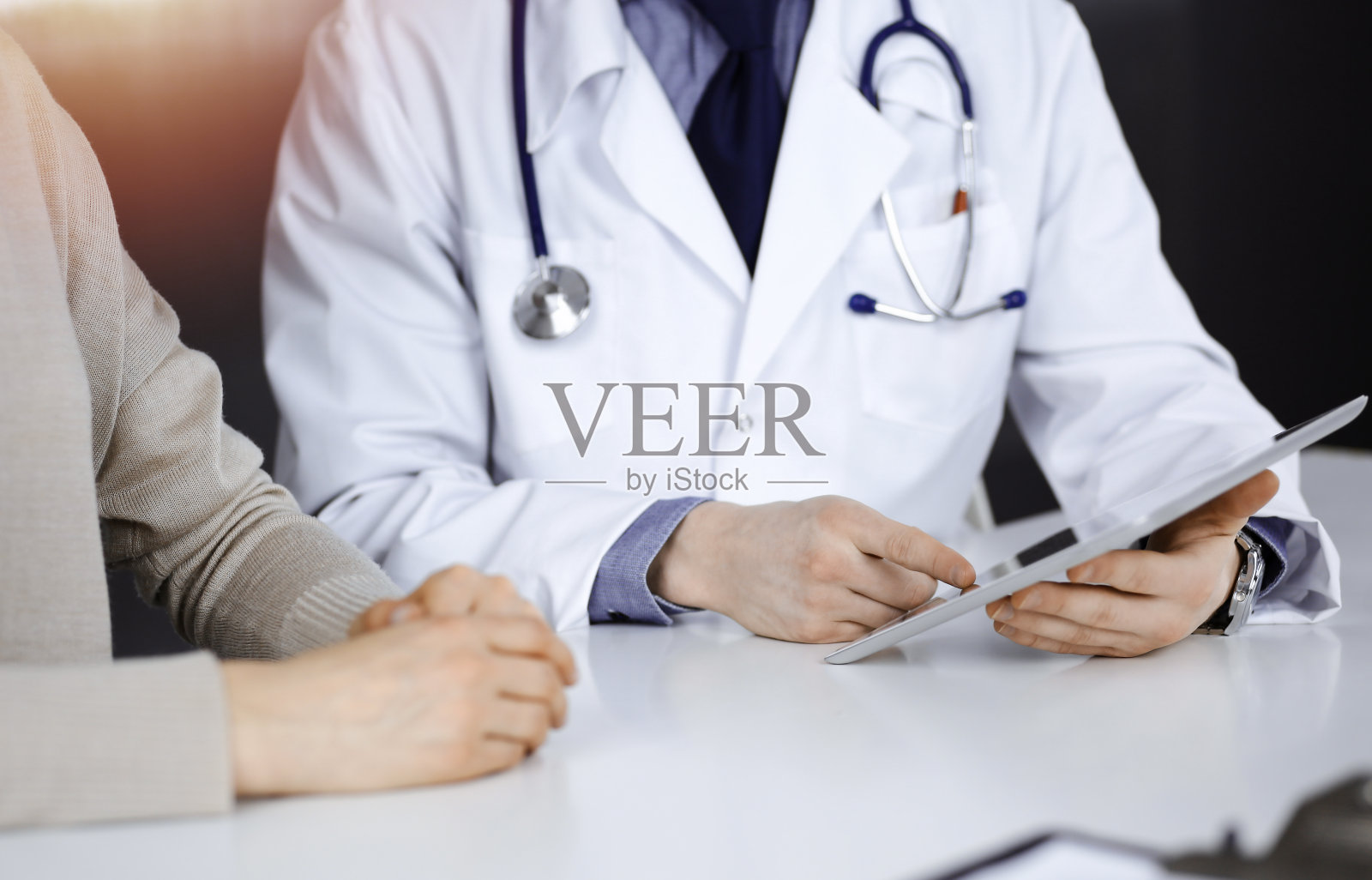 在黑暗诊所里，医生和患者使用平板电脑讨论病情照片摄影图片