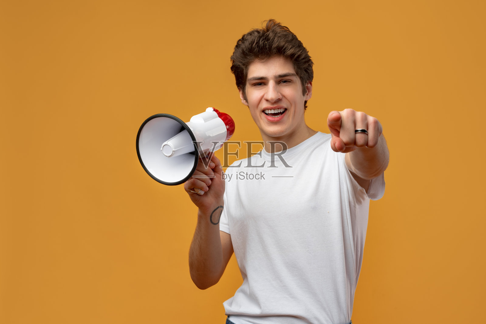 年轻人在黄色背景下对着扩音器喊话照片摄影图片