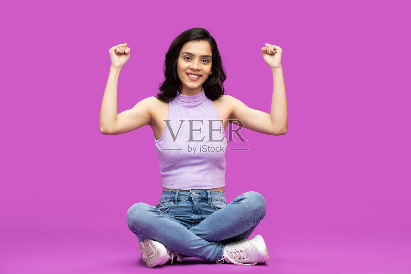 全长照片的女孩坐腿交叉赢举起手在紫色背景的股票照片照片摄影图片