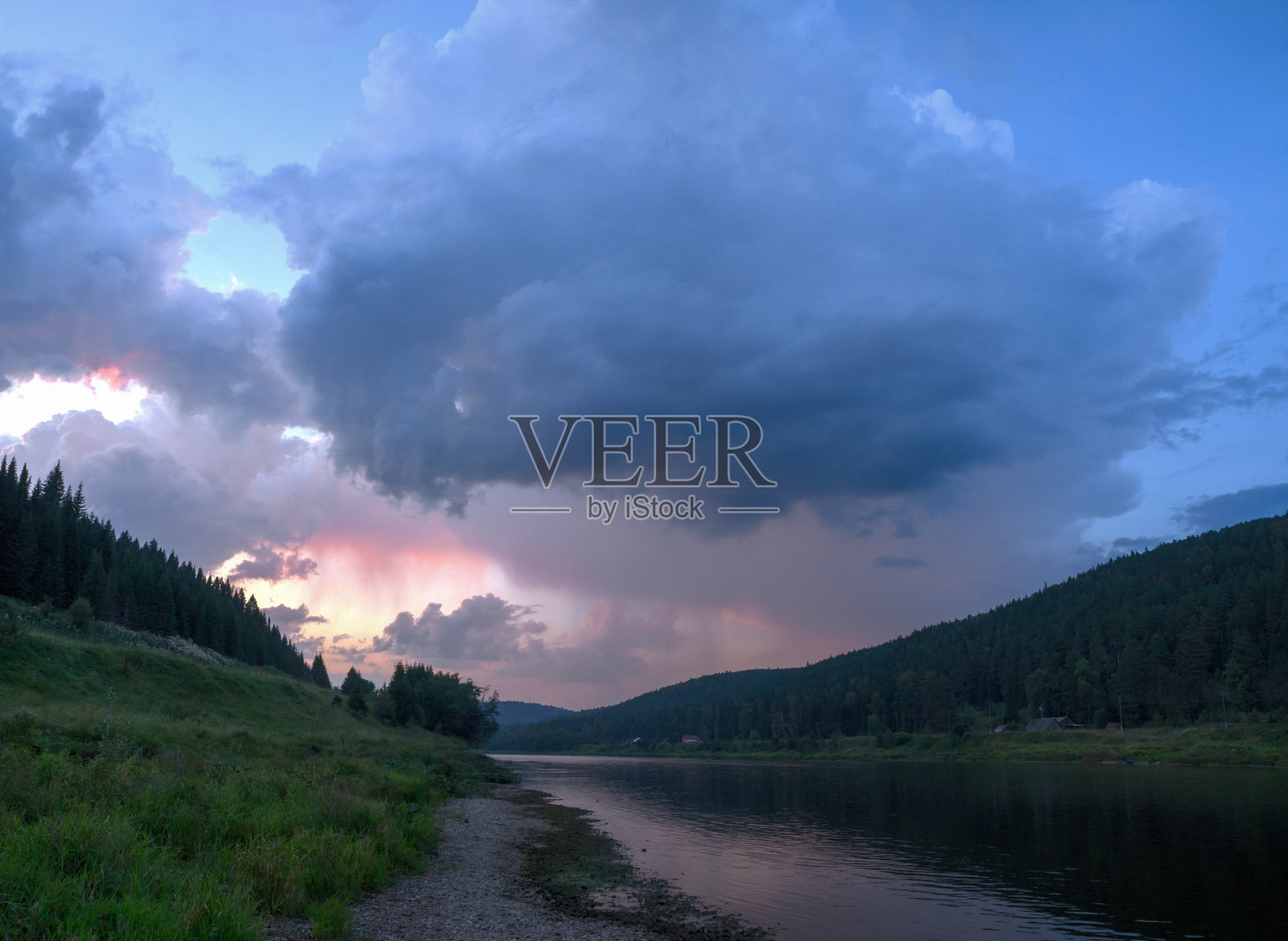 强大的雨云被美丽的河流上明亮的晚光照亮。照片摄影图片