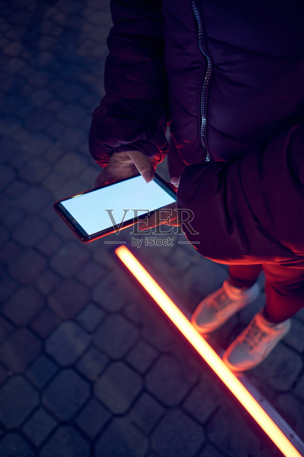 女人拿着手机过马路。照片摄影图片