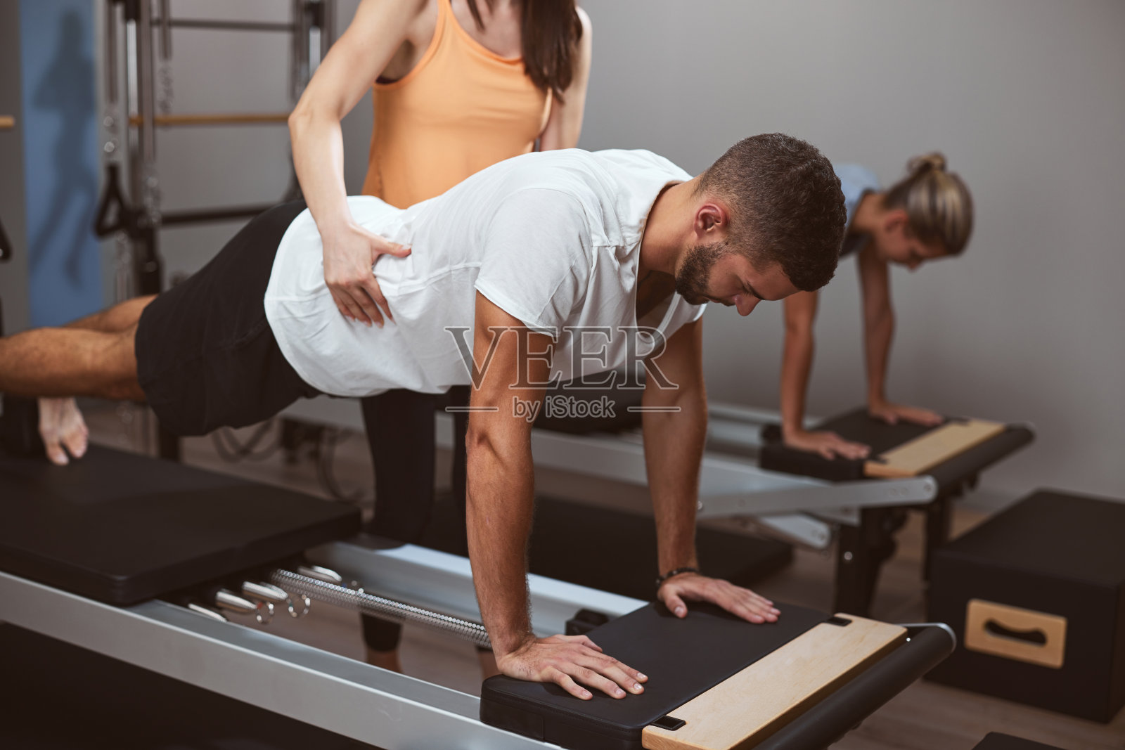 年轻的男女在私人教练的健身房锻炼。照片摄影图片