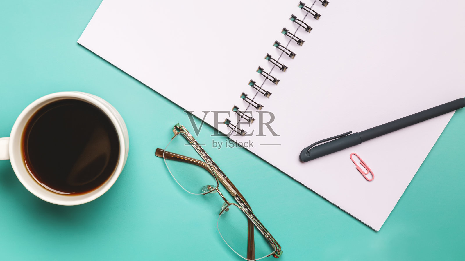 俯视图彩色工作台背景与空白纸笔记本，一杯咖啡。平铺彩色纸夹。记事本和笔。桌面模型，工作区，文具。照片摄影图片