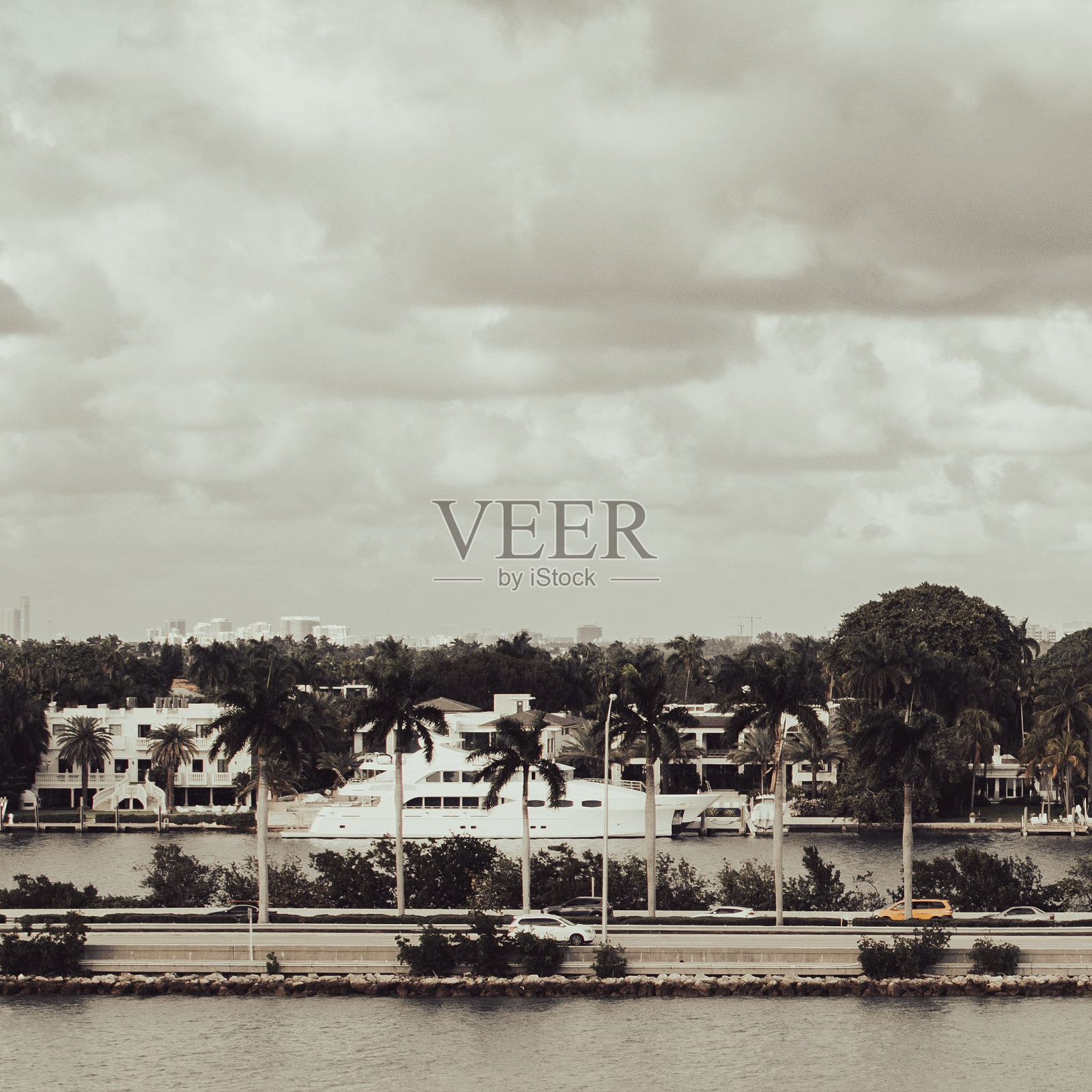 在多云的天空下，宁静的场景以水体和几座建筑物为背景。照片摄影图片