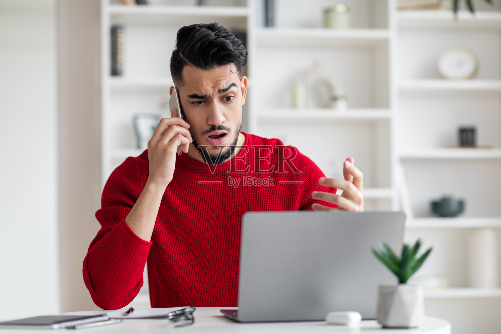 穿着红色衣服的阿拉伯中年女子在家用笔记本电脑打电话照片摄影图片