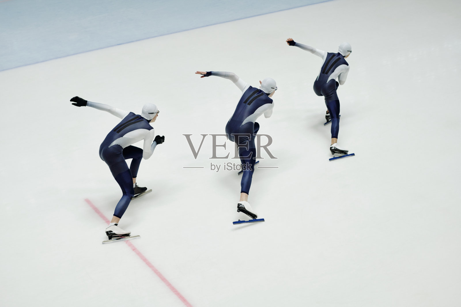 三个穿着运动服和冰鞋的年轻人沿冰场移动的高角度照片摄影图片