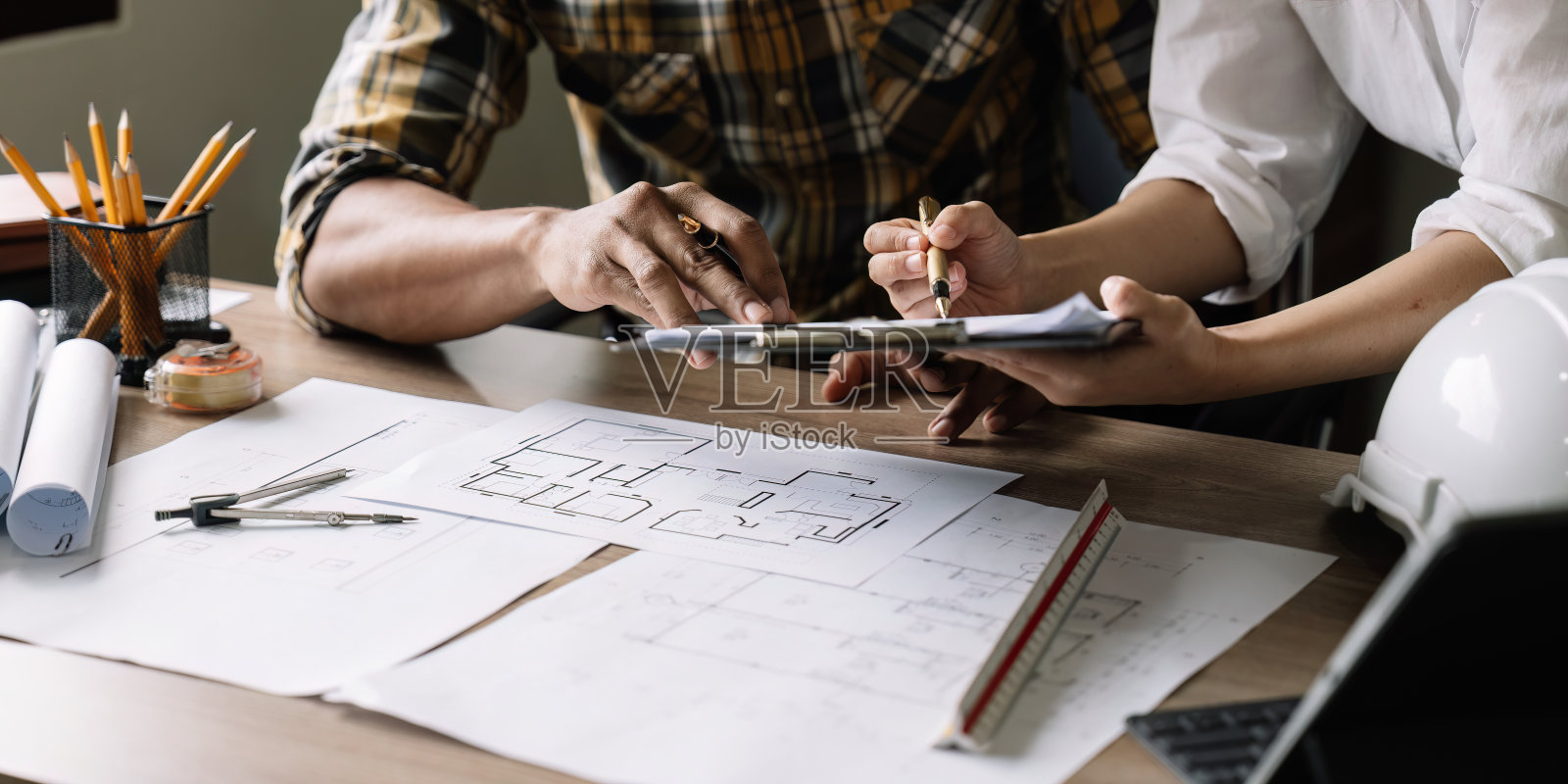 建筑工程团队在工作场所开会，计划绘制新的蓝图，为公寓大楼忙碌着照片摄影图片