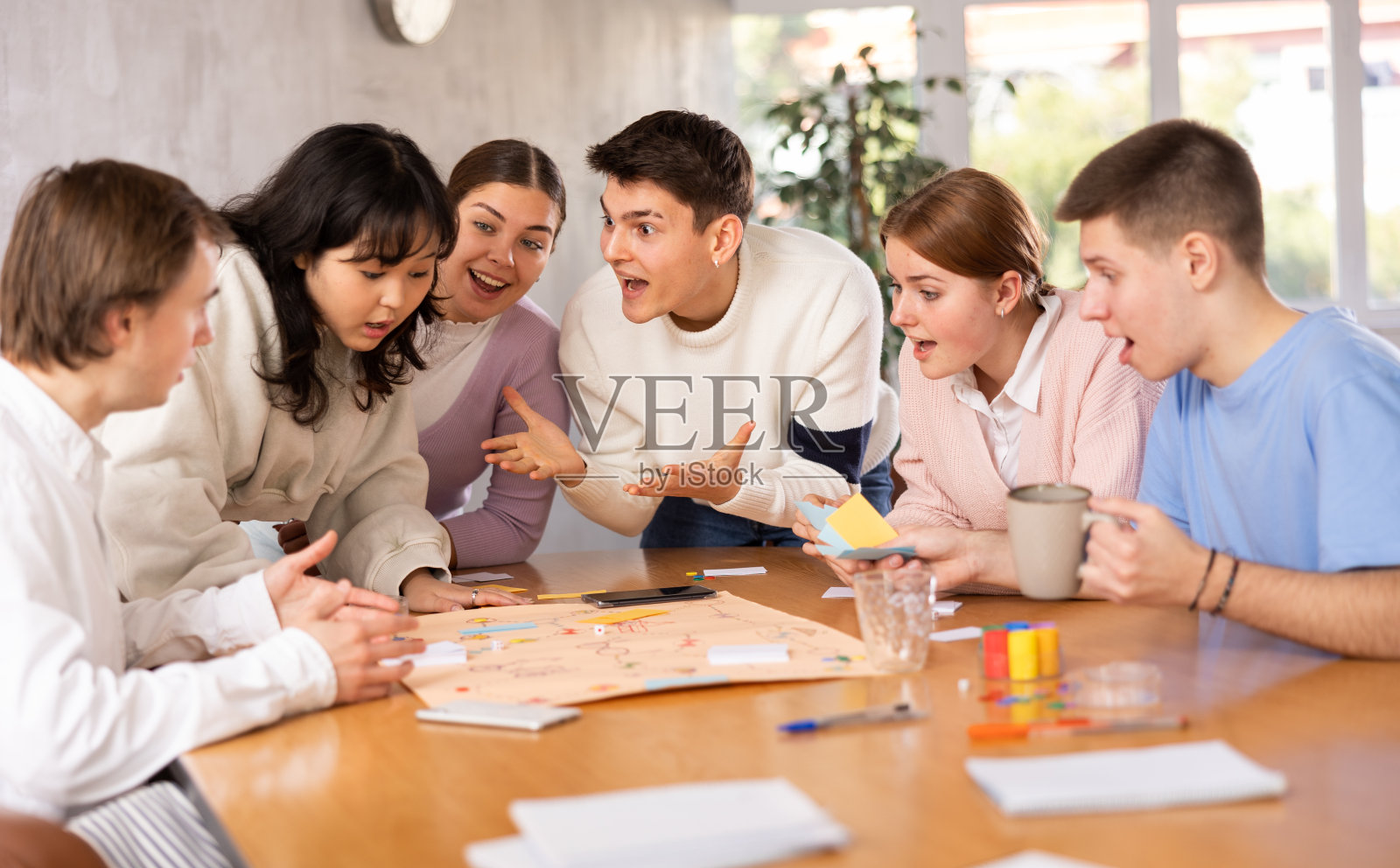 一群学生围着桌子玩棋盘游戏照片摄影图片