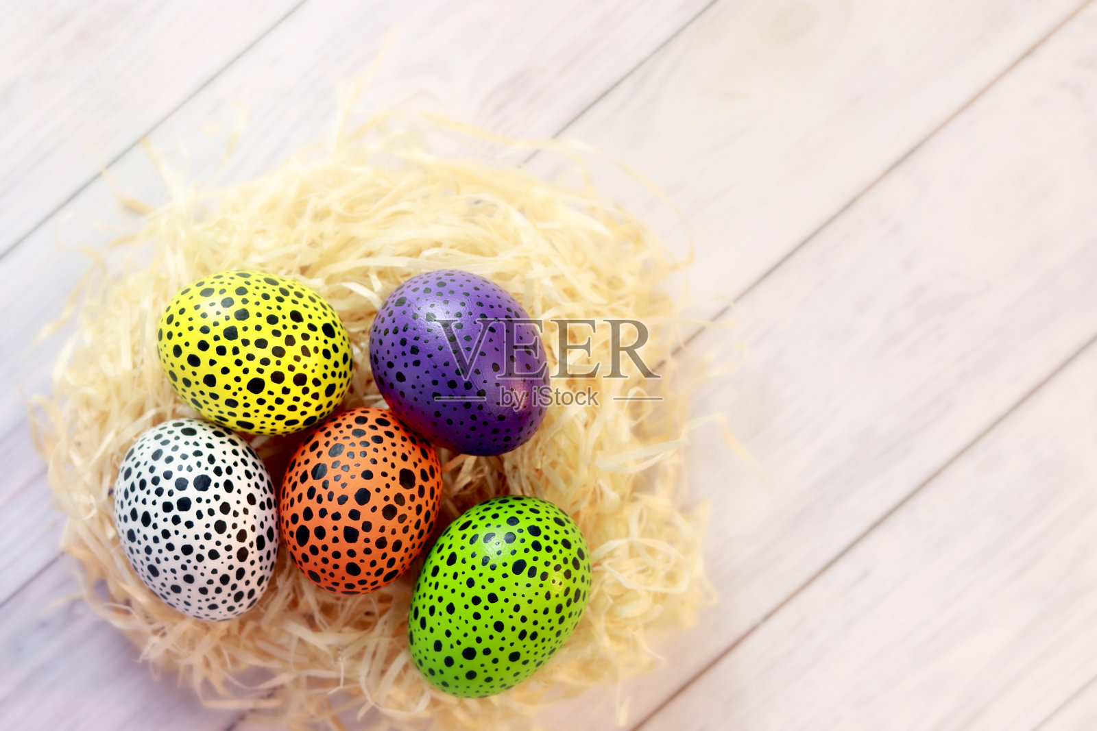 鸟窝里的彩蛋，俯视图。复活节快乐。鸡蛋涂上不同颜色的黑点。复活节彩蛋放在木桌上照片摄影图片