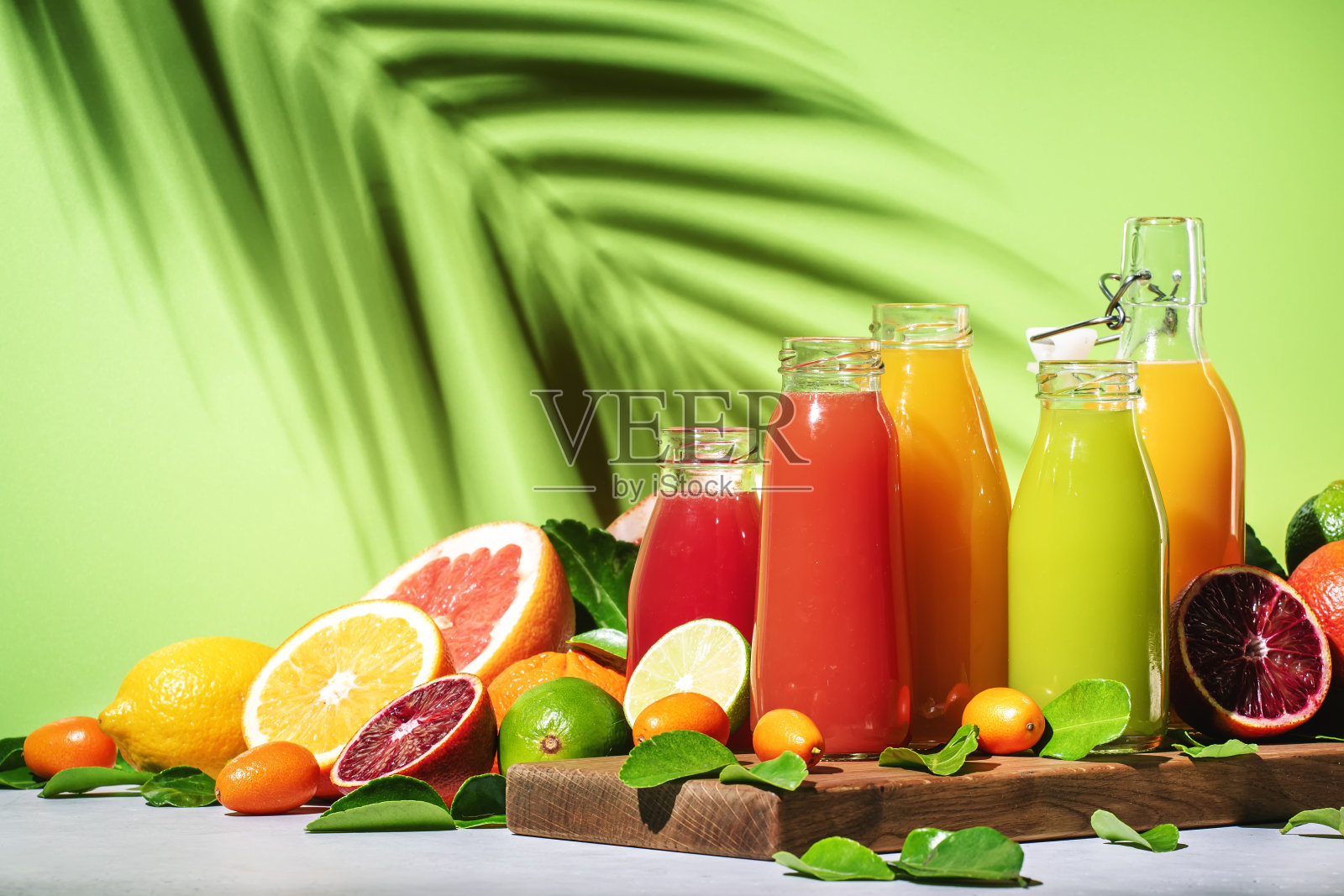 夏季饮料。柑橘果汁，新鲜和冰沙，食物背景。混合不同的完整和切块水果:橙子，葡萄柚，酸橙，带叶子的橘子和瓶装饮料照片摄影图片