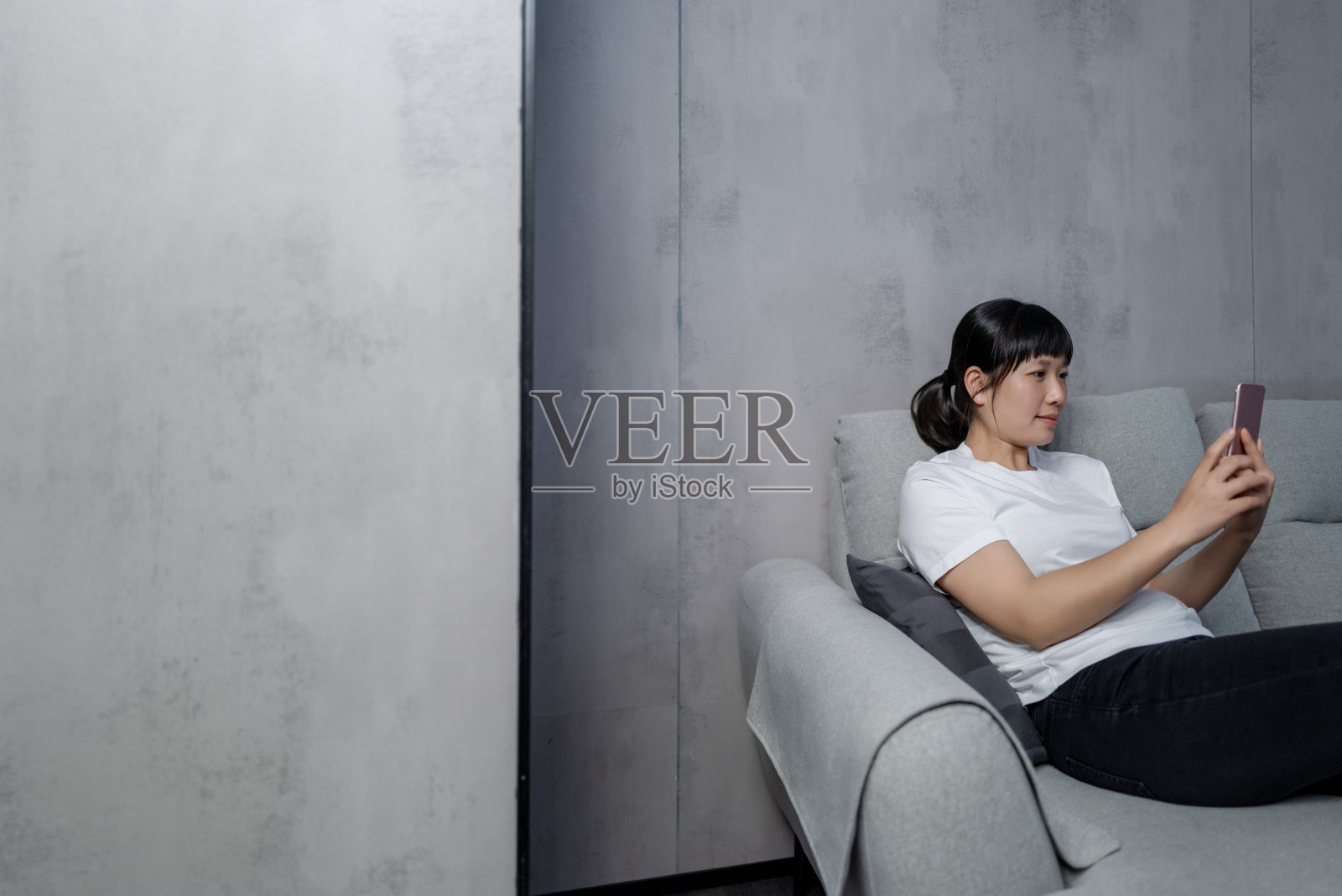 一个女人坐在沙发上用手机照片摄影图片