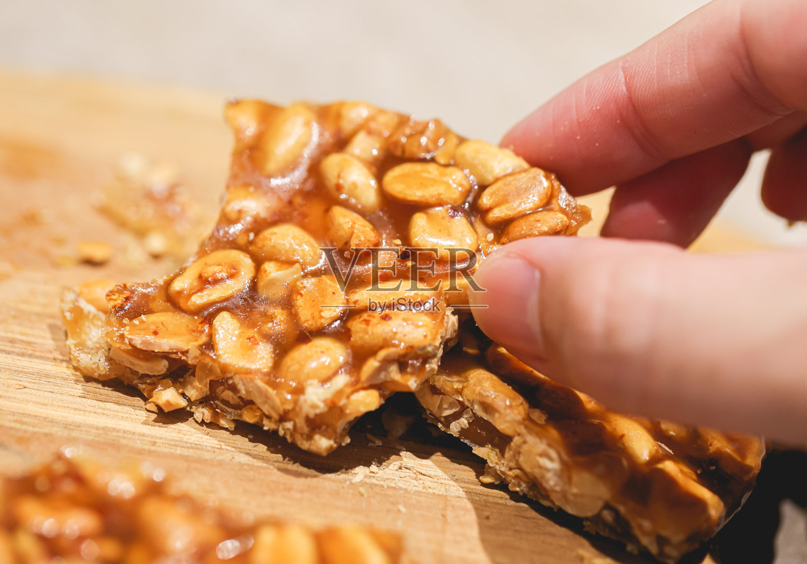 一个男人拿着一块放在木板上的花生糖。特写照片。照片摄影图片