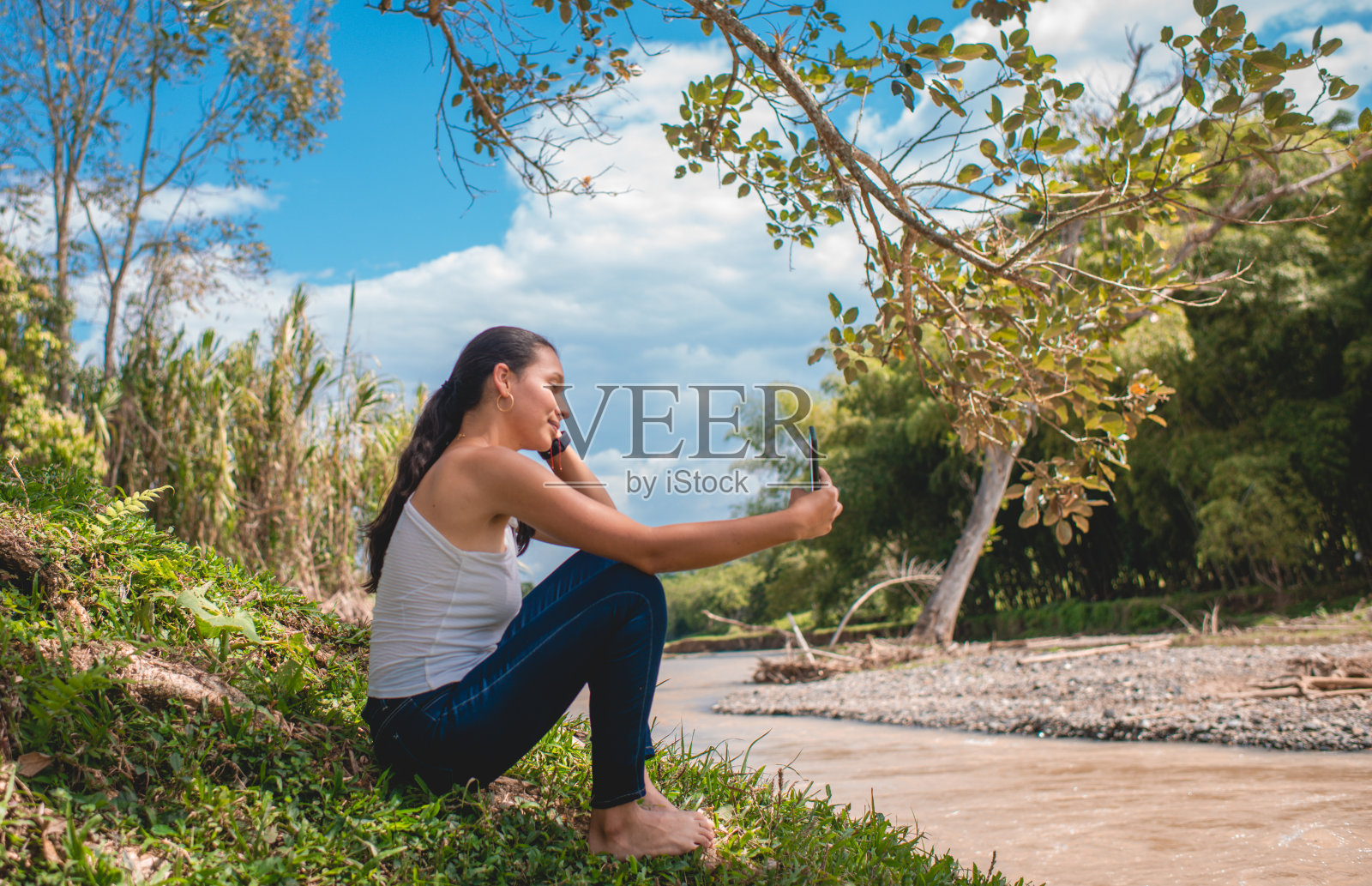 一名年轻女子站在河边。照片摄影图片