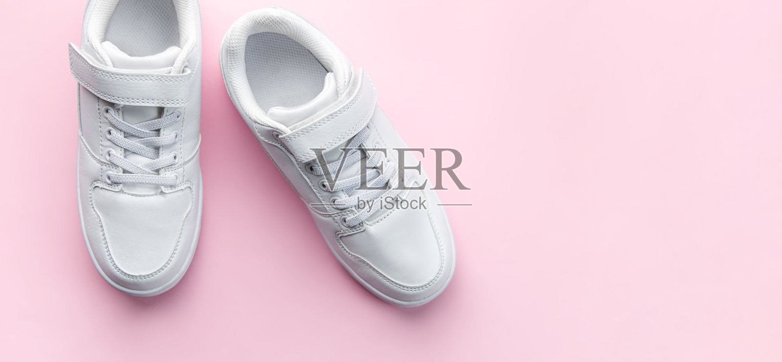 粉色背景的白色运动鞋。照片摄影图片