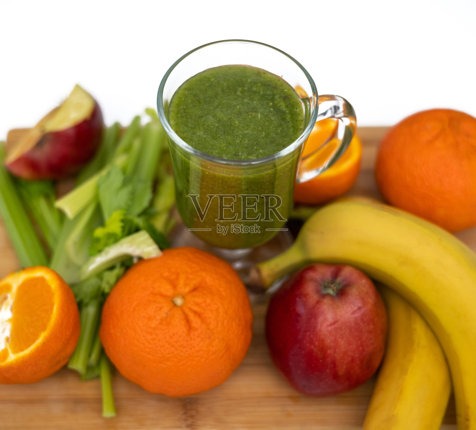 苗条的女人在厨房用芹菜、苹果、猕猴桃和橘子做健康的奶昔照片摄影图片