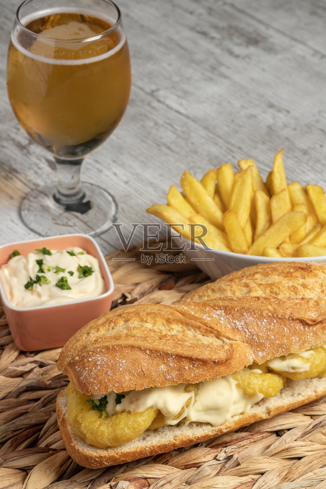 典型的西班牙鱿鱼三明治配蛋黄酱蒜末和欧芹。一点褪色的薯条和一杯冰啤酒。tapas的概念，乐趣和美食。照片摄影图片