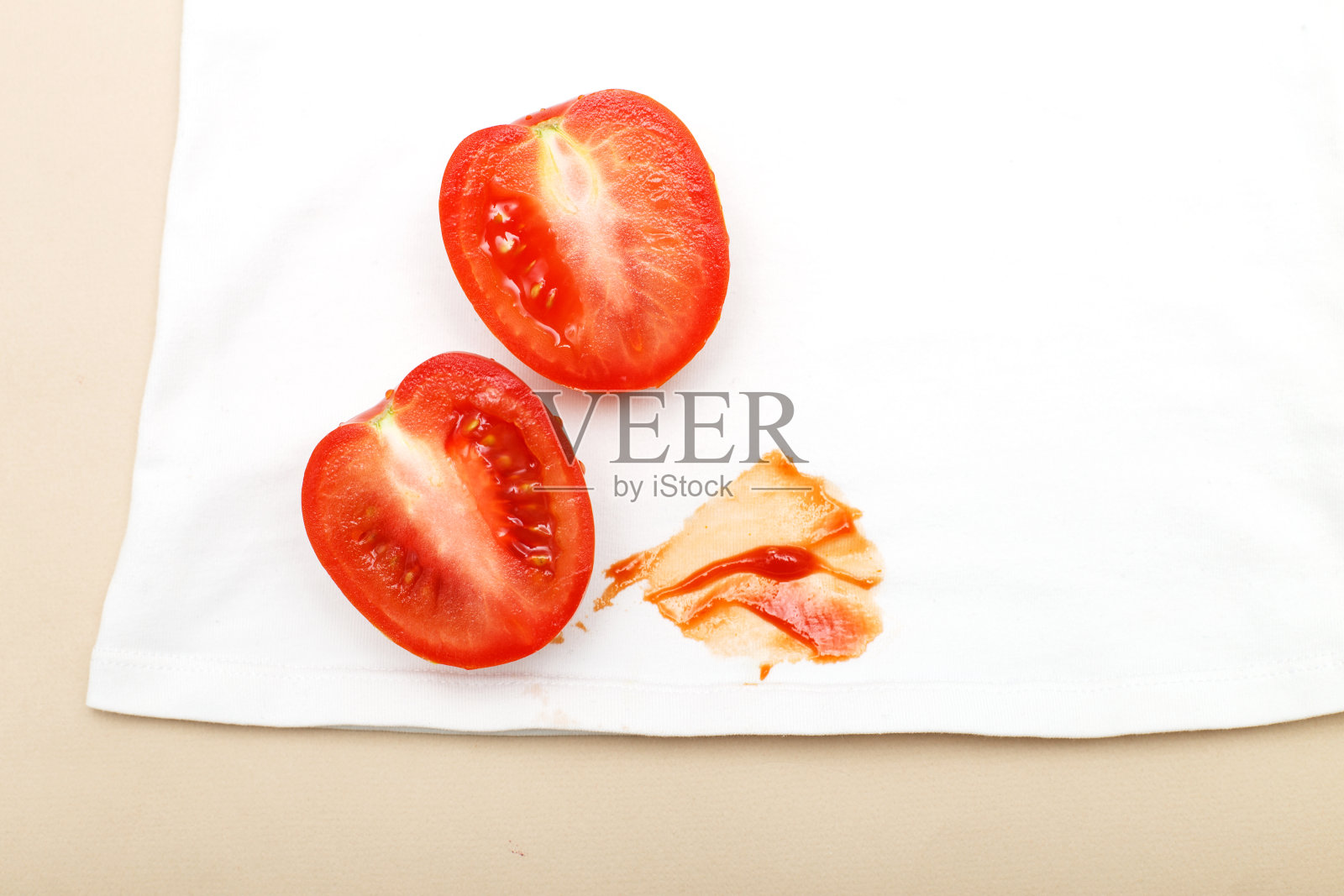 西红柿和番茄酱污渍在白色衬衫衣服在米色的背景照片摄影图片