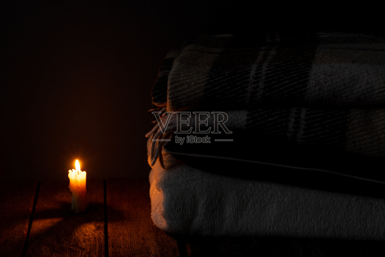 在黑暗的卧室里，毯子和枕头叠在一起，背景是火蜡烛照片摄影图片