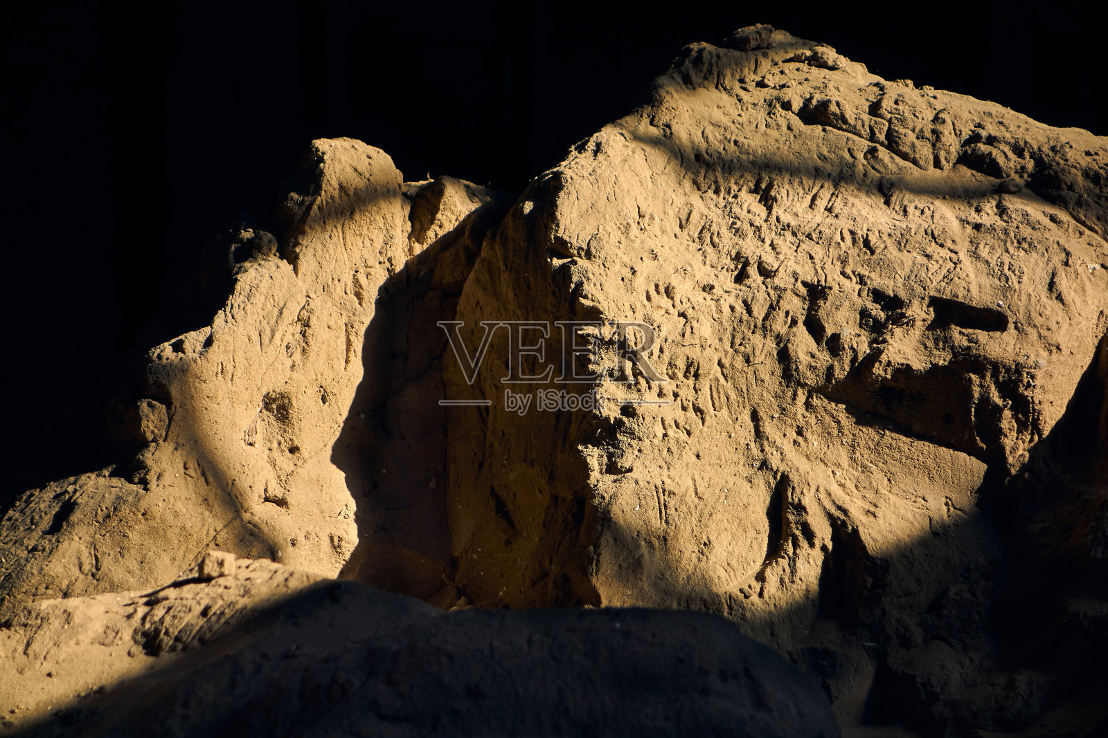 一堆旧沙躺在一个黑暗的仓库里，阳光照亮了这些石化的沙子照片摄影图片