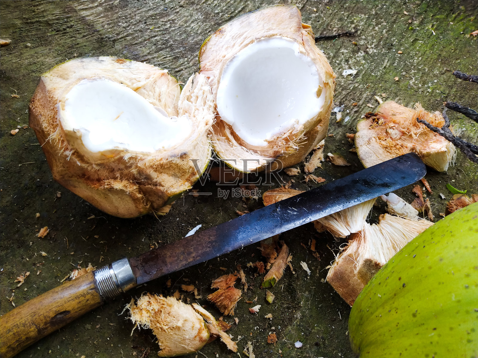 一个年轻的绿色椰子，旁边有一把砍刀照片摄影图片