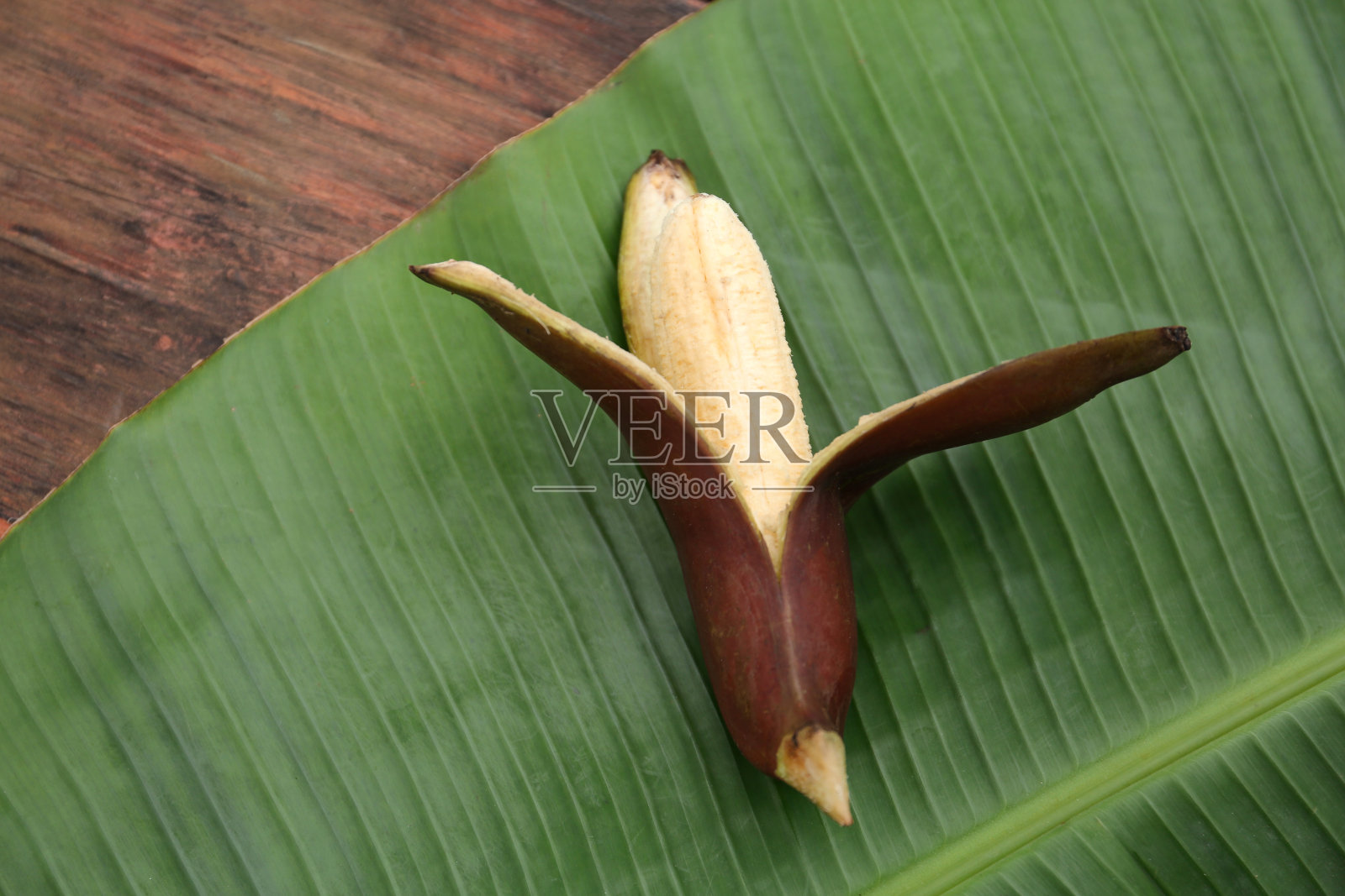 美味的紫香蕉和新鲜的叶子放在木桌上，俯视图照片摄影图片