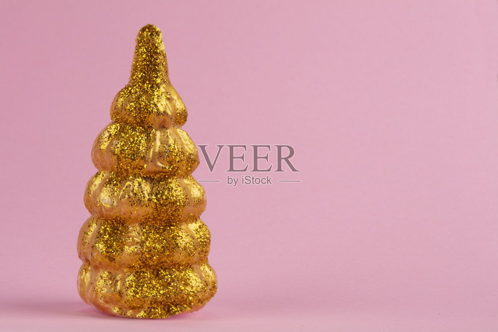 圣诞组成。粉色背景上的金色圣诞树。节日快乐。最小的新年概念。照片摄影图片