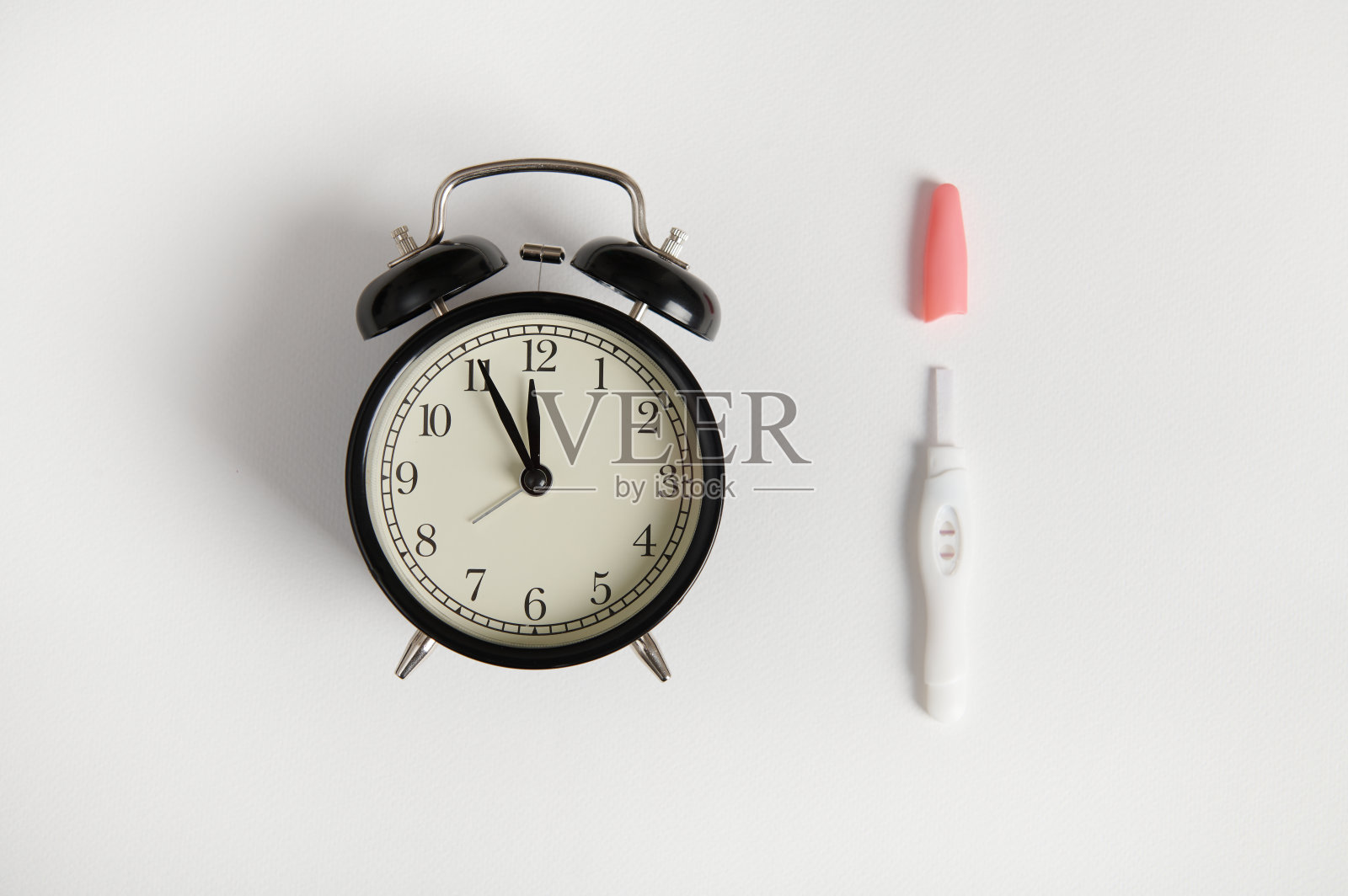 静物与黑色复古闹钟和喷墨阳性怀孕测试孤立的白色背景照片摄影图片