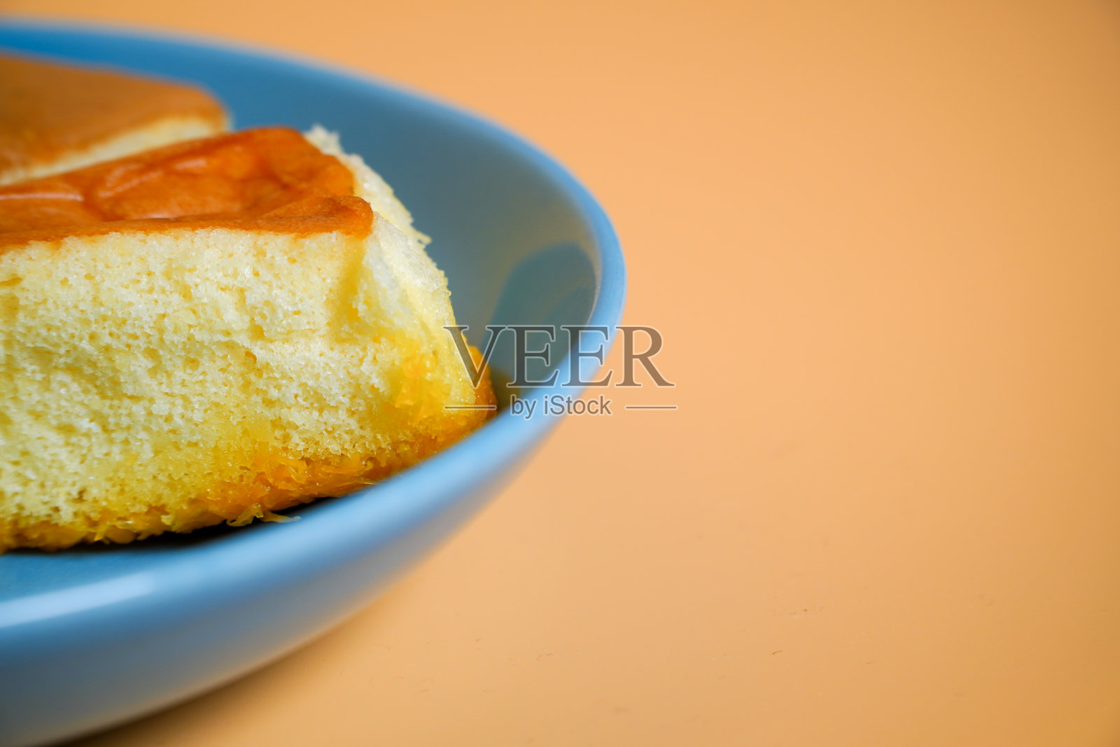 蓝色盘子上有小椰子的雪纺蛋糕，橙色背景照片摄影图片