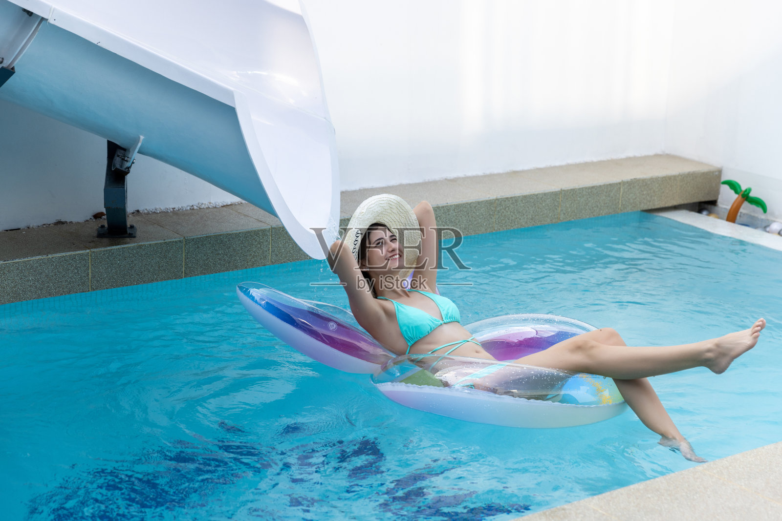 女人在比基尼与橡胶充气浮子。游泳池里穿泳装的女人在游泳管上。美丽的女孩在游泳池从上面，放松游泳充气环。照片摄影图片