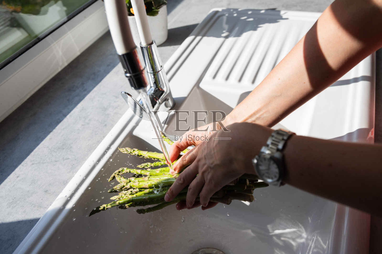 手洗鲜绿芦笋菜，用滤器冲洗绿芽菜照片摄影图片