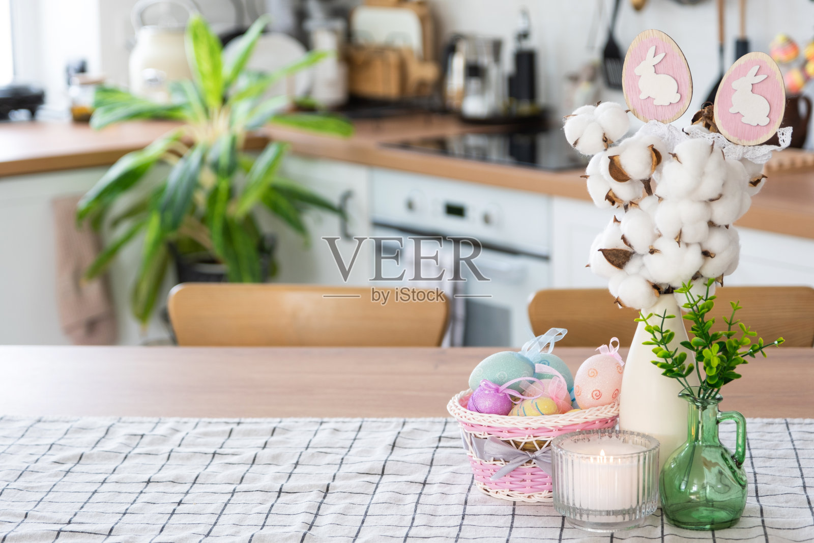 复活节装饰的彩色鸡蛋在篮子和兔子在厨房的桌子上的乡村风格。乡村别墅的喜庆内饰照片摄影图片