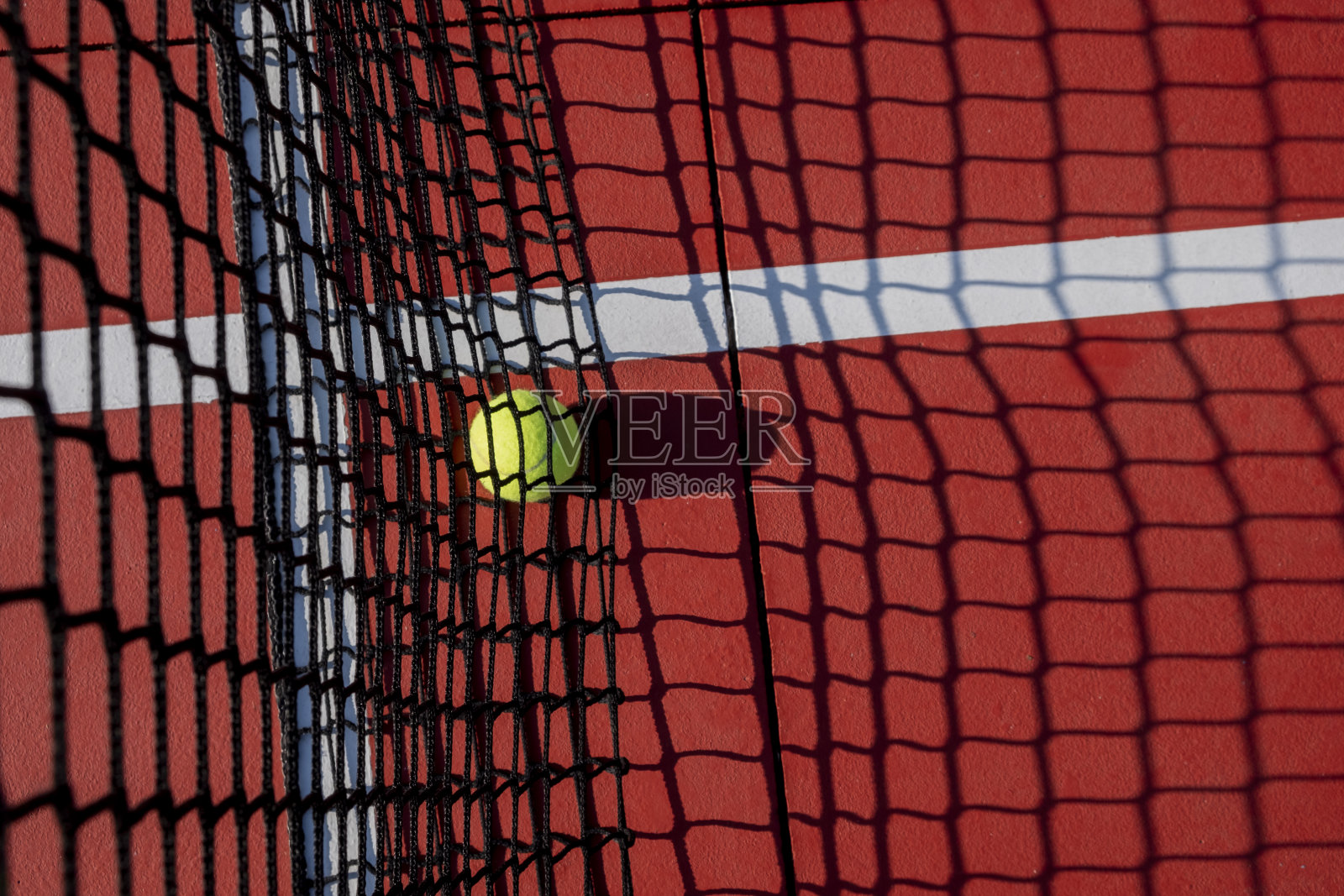 选择性聚焦，红色网球场网上的一个球照片摄影图片