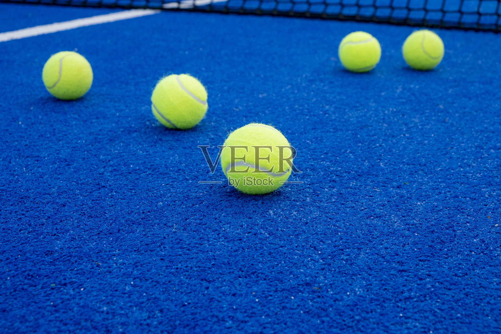 选择性聚焦，几个球在一个蓝色球拍网球场的表面照片摄影图片