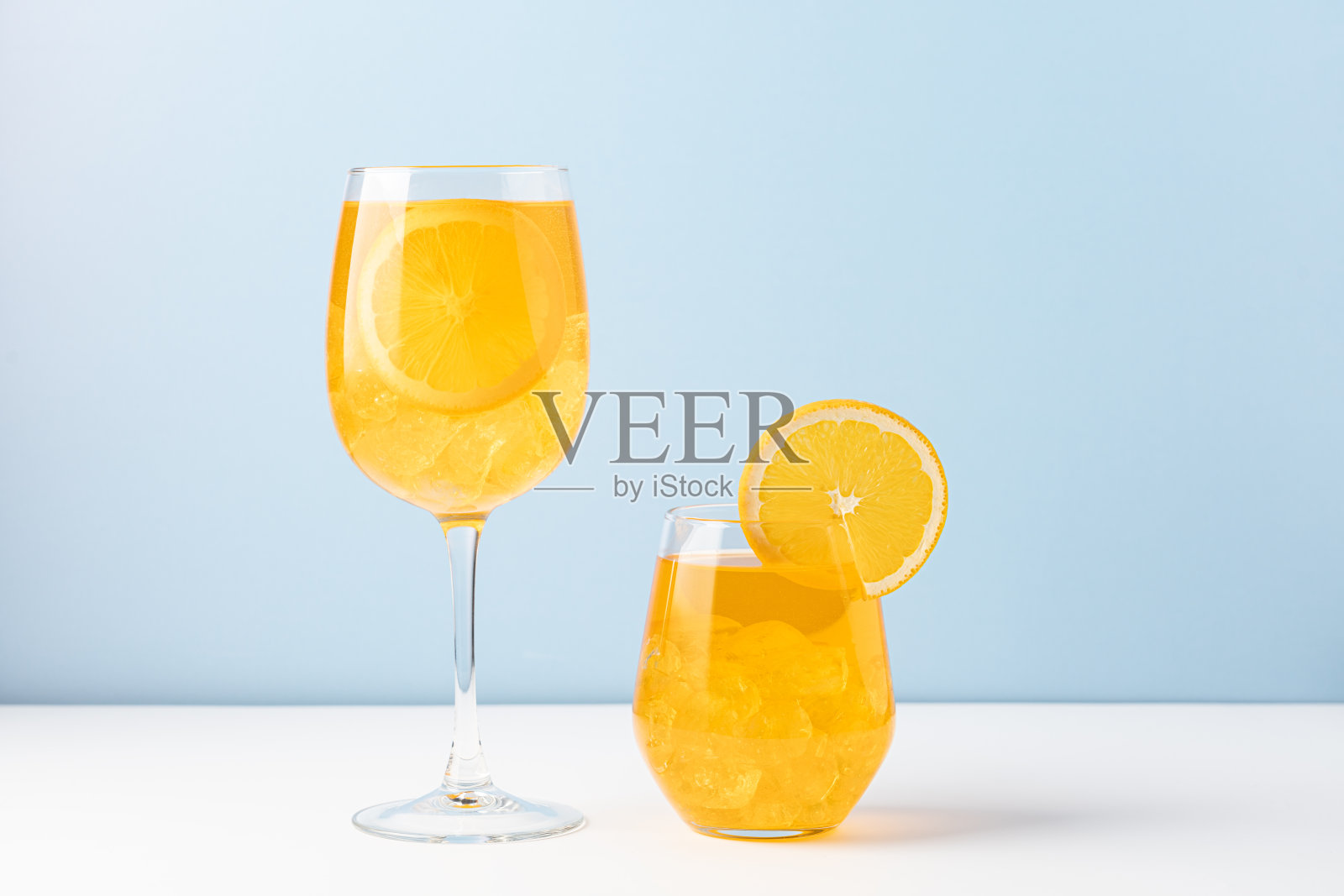 橙色饮料，蓝底加冰。照片摄影图片