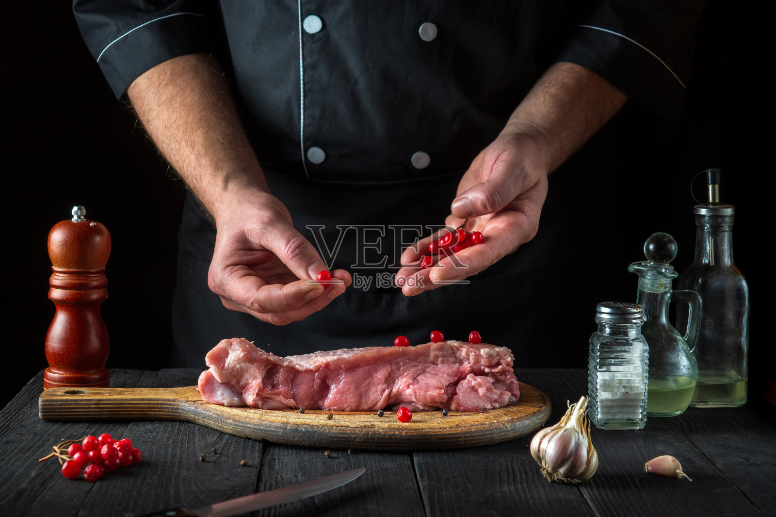在餐厅的厨房里，厨师正在准备生牛犊肉。在烤之前，厨师会把香菇放在牛肉上。国家的菜照片摄影图片