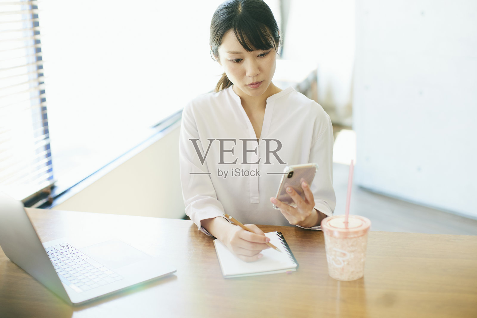 年轻的亚洲女人在靠窗的办公室工作照片摄影图片