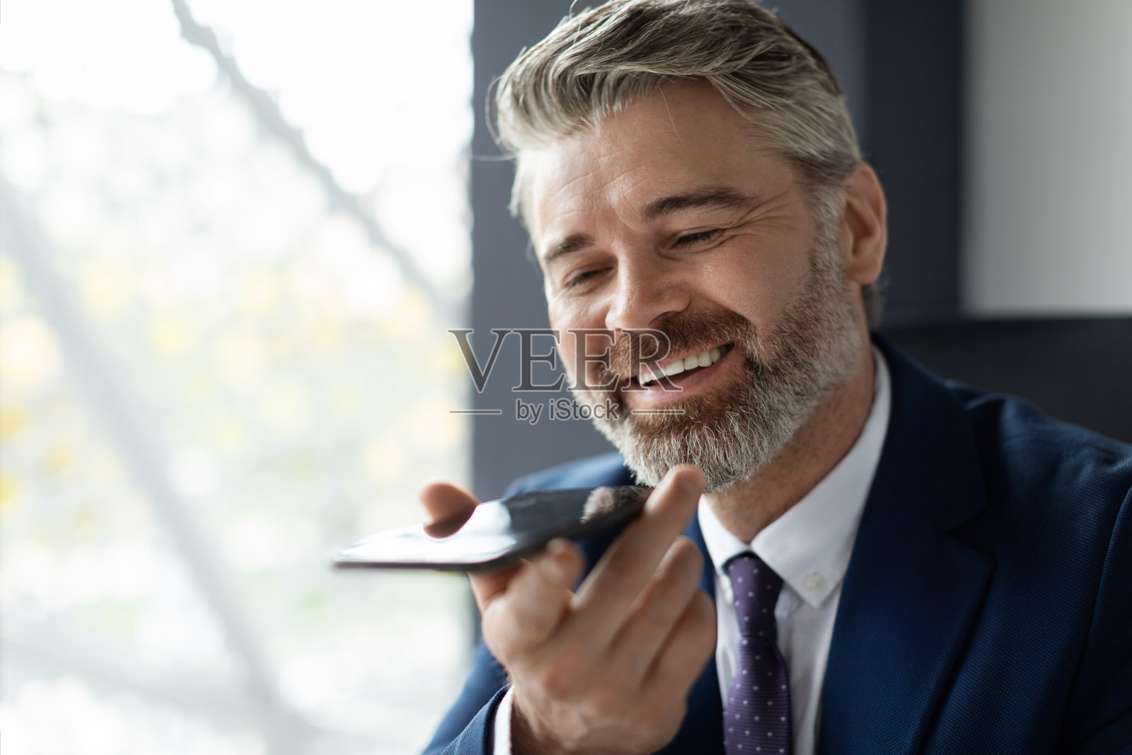 英俊的中年商人在办公室工作场所录制语音信息照片摄影图片