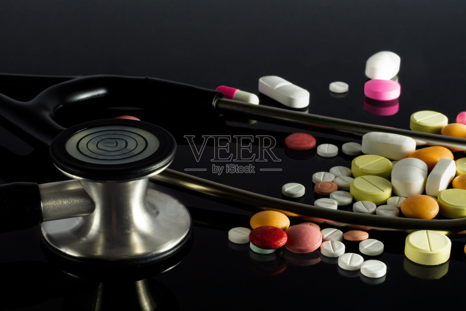 黑色背景上有药丸的听诊器特写镜头照片摄影图片